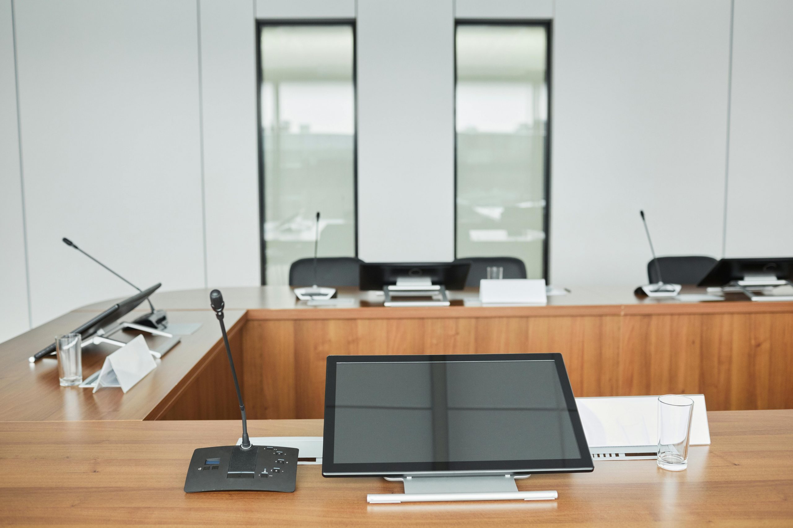 A conference room table with personal displays and microphones for each participant.